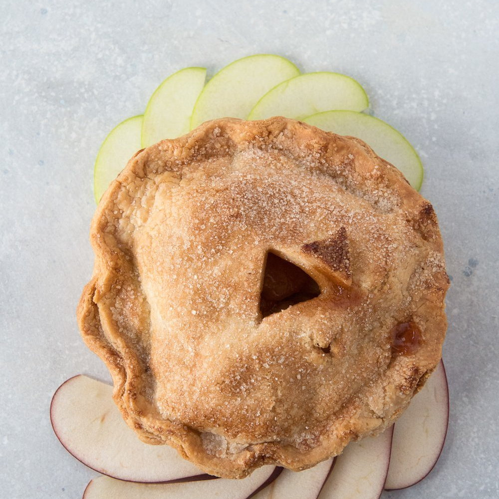 top view gluten free pie surrounded with sliced red green apples