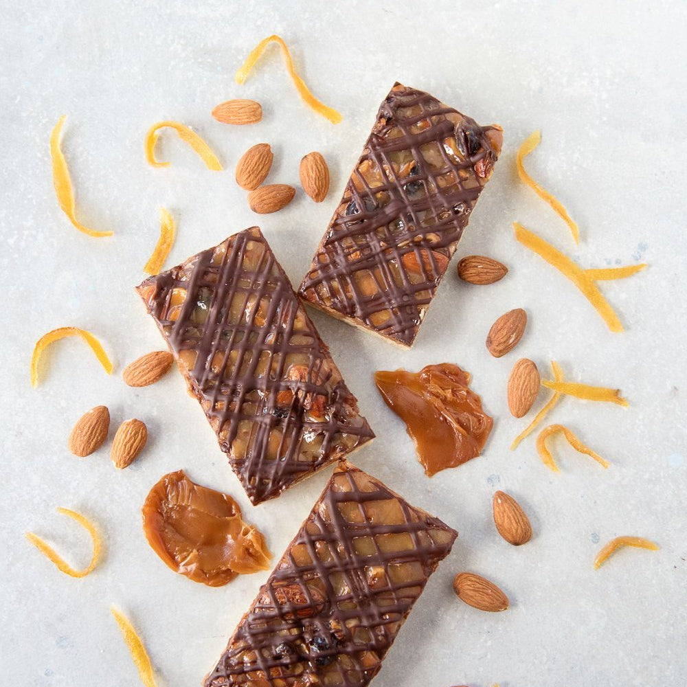 top view 3 gluten free florentine bars showing chocolate drizzle on top of caramel, almonds, cranberry & candied citrus topping