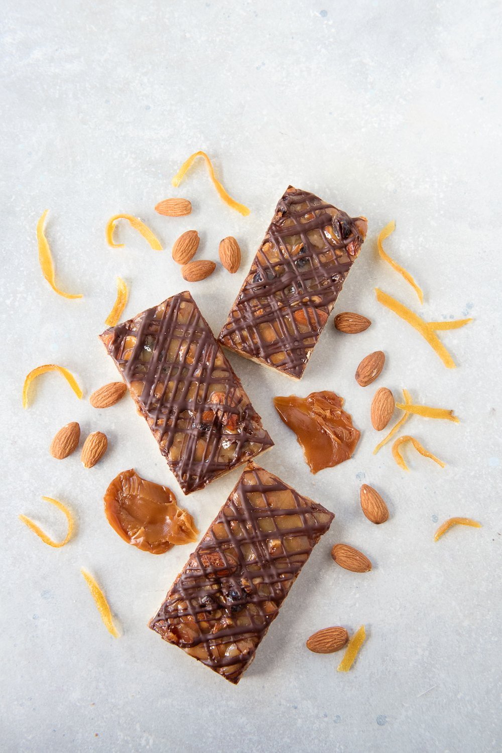 top view 3 gluten free florentine bars showing chocolate drizzle on top of caramel, almonds, cranberry & candied citrus topping