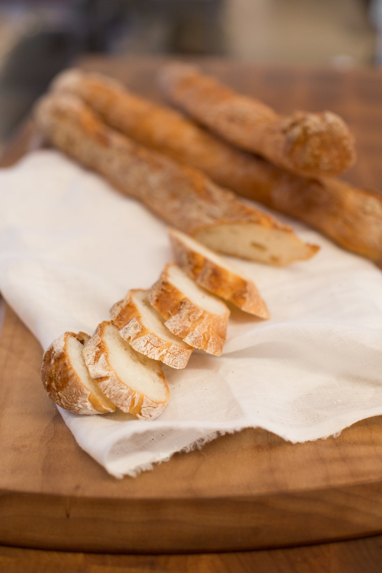 gluten free baguette slices on white cloth on wood cutting board